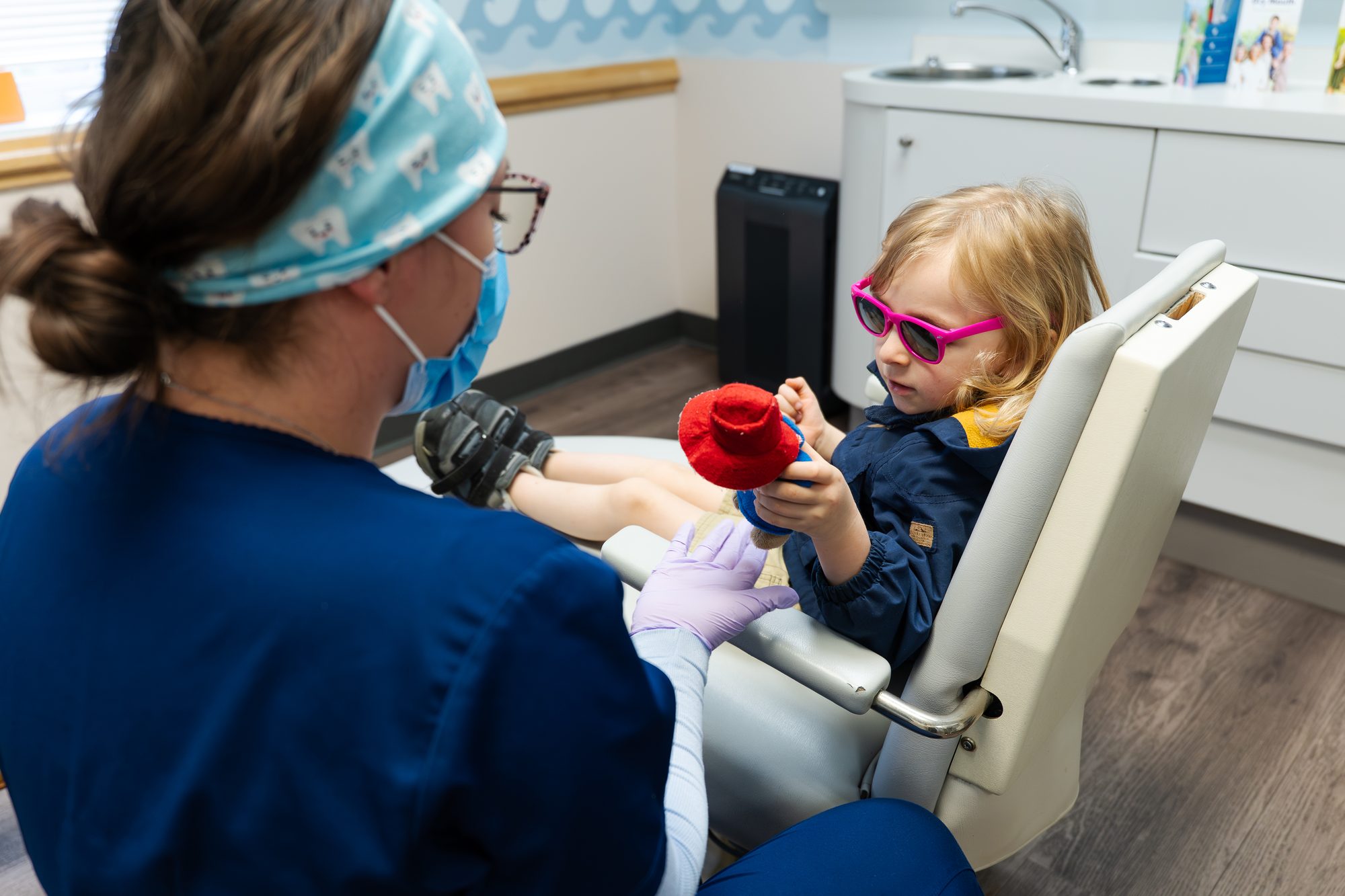 Child in pink sunglasses in dental chair at Falmouth Pediatric Dentistry in Falmouth, ME