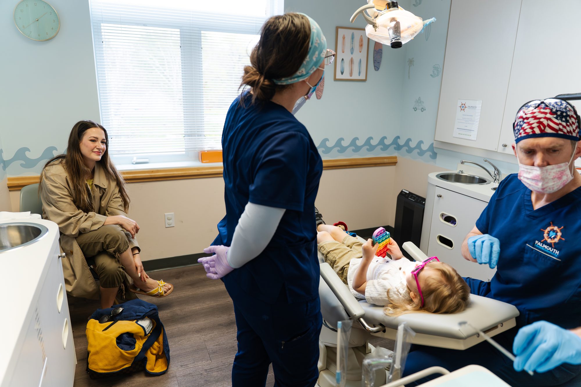 Child in dental chair at Falmouth Pediatric Dentistry in Falmouth, ME with two dental professionals