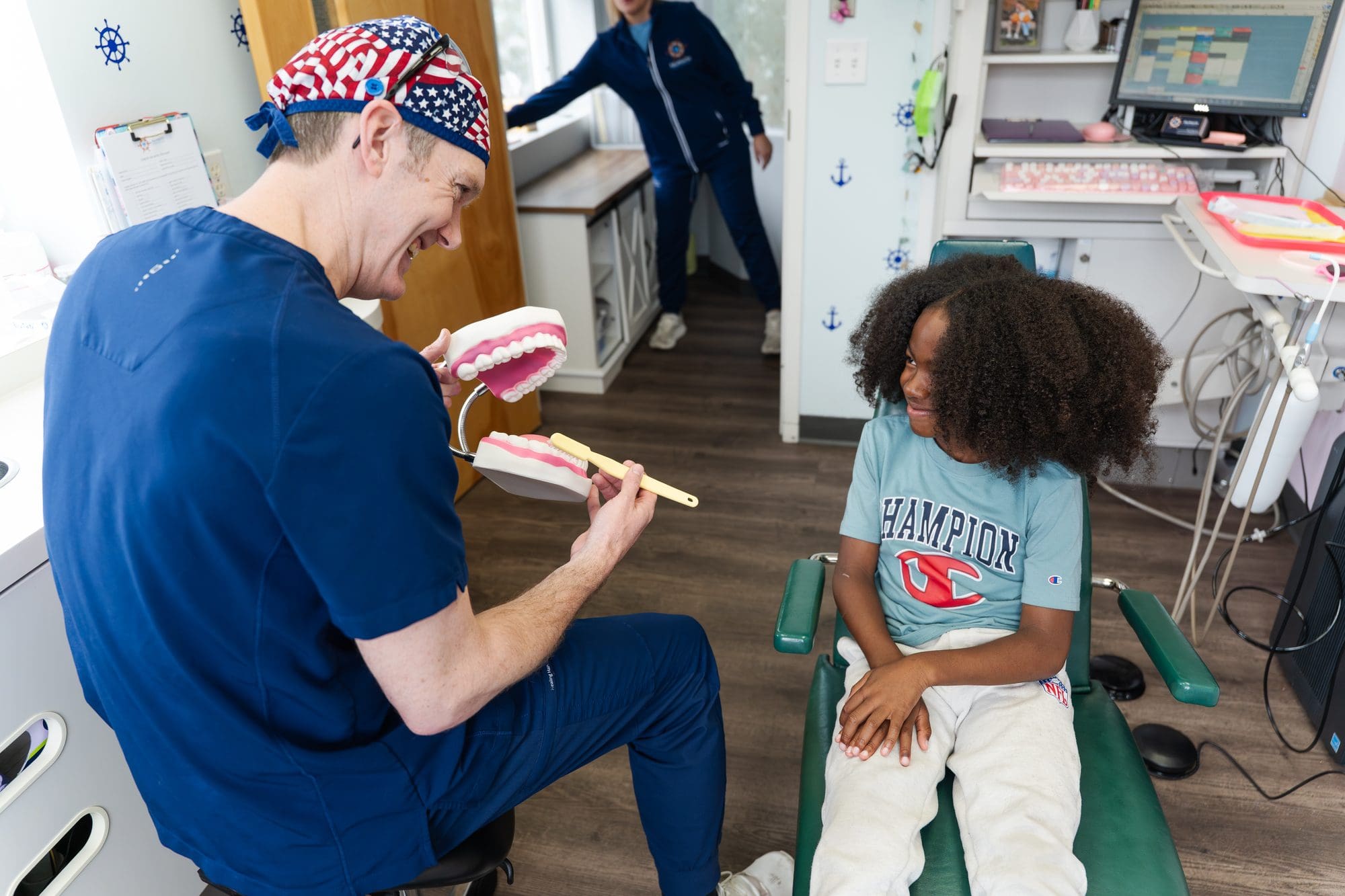 Dentist demonstrating tooth brushing with model to child at Falmouth Pediatric Dentistry in Falmouth, ME